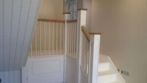 A staircase with white steps and wooden handrails, leading to a door with a window above it. - Stunning coastal annex with spectacular sea views (Perranuthnoe)