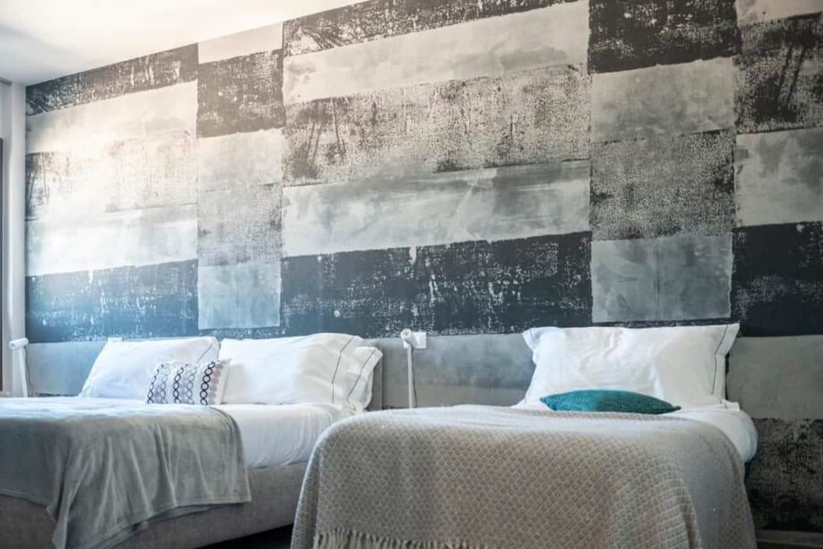 A hotel room with two beds, a large window, and a textured wall.
