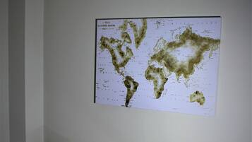 A room with two chairs and a small table, a world map on the wall, and a plain white wall.