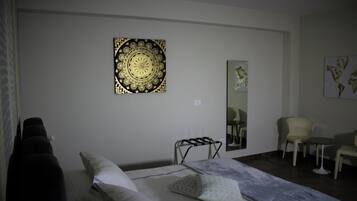 Ein Hotelzimmer mit einem Bett, einem Sessel, einem kleinen Tisch und einem Wandbild.