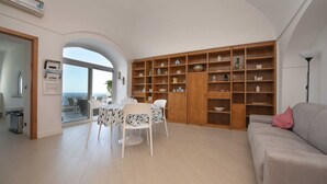 A spacious living area with a dining table and chairs, a built-in wooden shelving unit, and a view through an archway to the outside. - Casa Margherita ..... Positano, perfect location for your holiday in Positano (Positano)