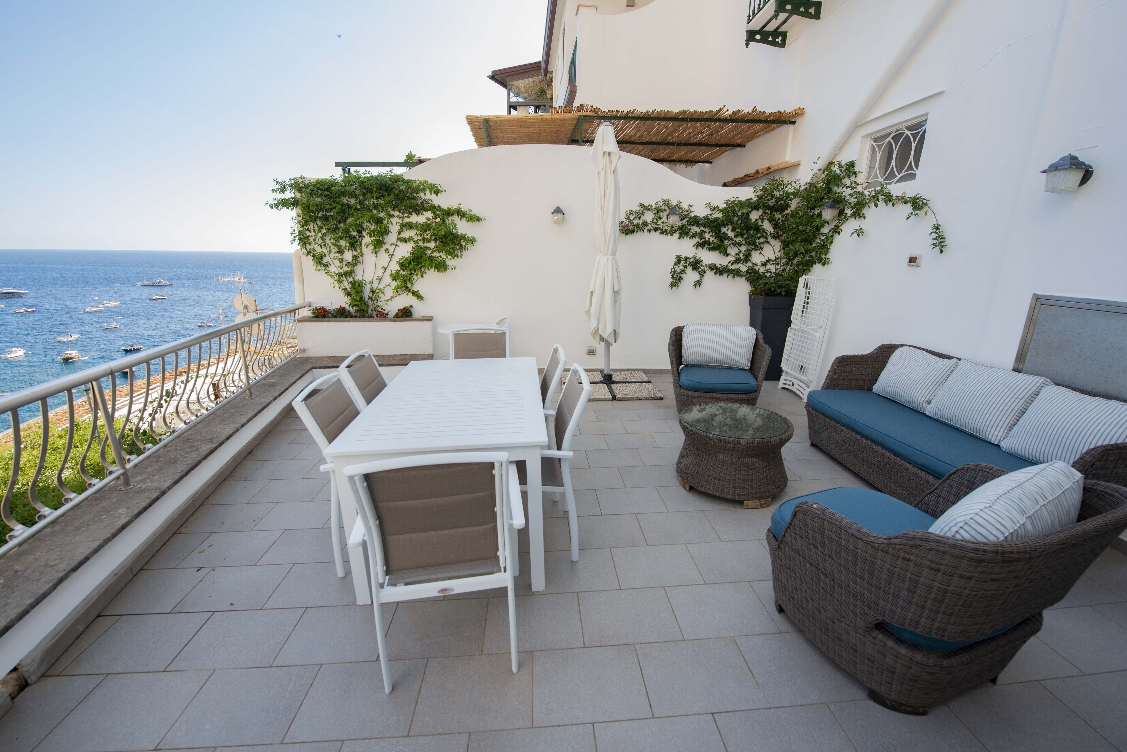 Une terrasse avec une table et des chaises, un canapé et des plantes en pot.