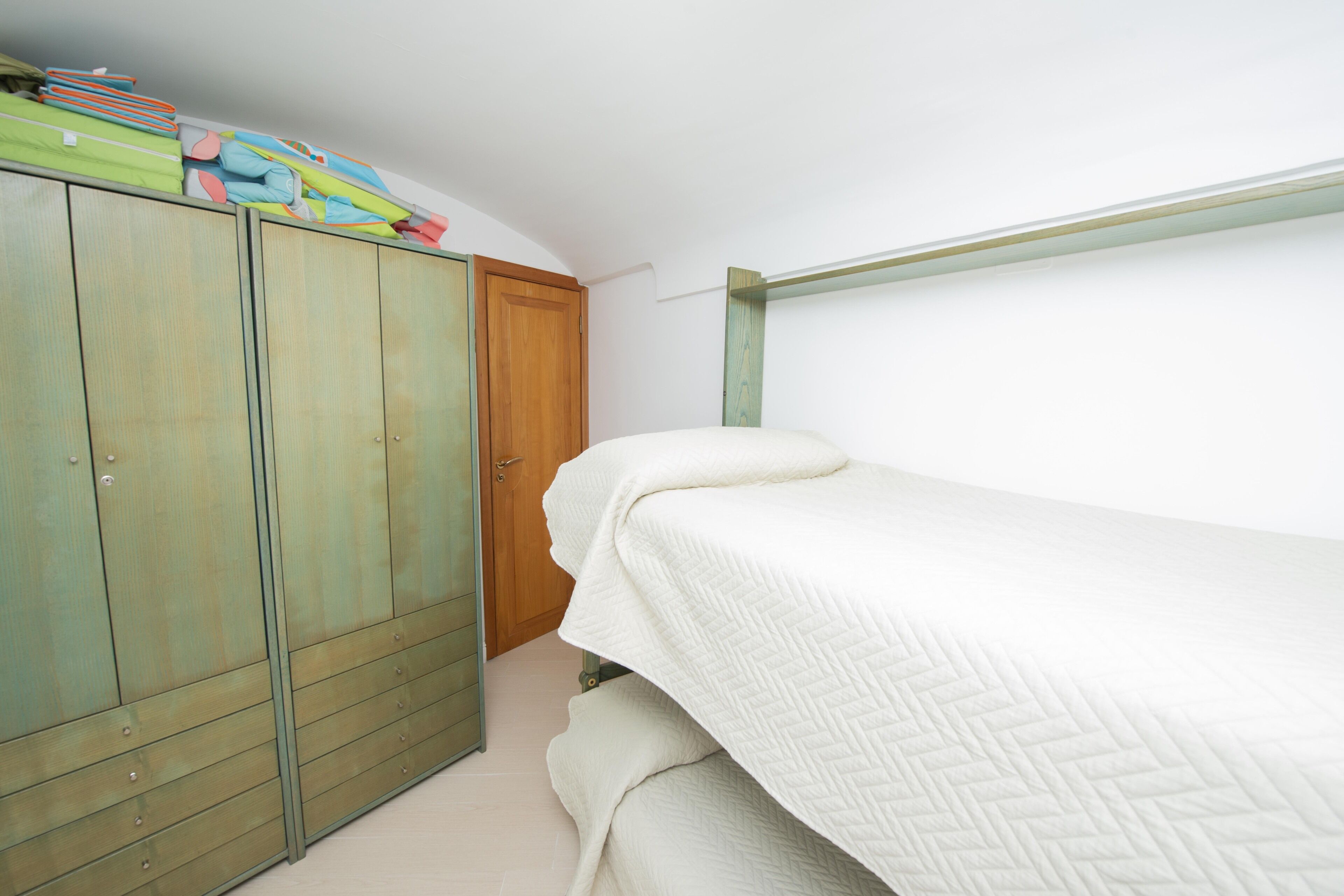 Un dormitorio con una litera, un armario y una puerta.