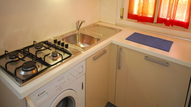 A compact kitchen with a gas stove, sink, and washing machine.