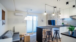 A modern kitchen with a black island, bar stools, pendant lighting, and a patterned backsplash. - VISENTO Apartments Kreta 52-54 (Bialystok)