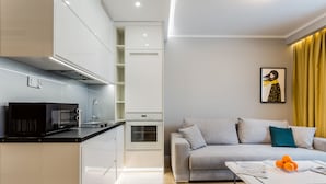 A modern kitchen with white cabinets, a black microwave, and a built-in oven. - VISENTO Apartments Kreta 52-54 (Bialystok)