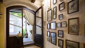 Un couloir doté d’un sol carrelé, d’une porte en bois et d’un mur orné de tableaux encadrés.