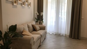 A living room with a beige sofa, a coffee table, and several potted plants. - In Matera "Sotto i pini" - COMFORT AND NEAR THE SASSI (Matera)