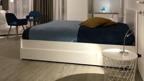 A modern hotel room with a bed, a desk, a chair, a lamp, and a mirror. - In Matera "Sotto i pini" - COMFORT AND NEAR THE SASSI (Matera)