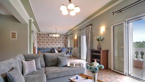 Ein Wohnzimmer mit grauem Sofa, einem Holztisch und einem Bücherregal voller Bücher.