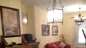 A living room with a fireplace, a red sofa, striped ottomans, a glass coffee table, and a chandelier. - Beautiful house rociera to enjoy with your people (El Rocío)