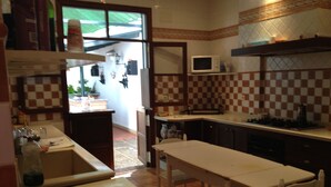 A kitchen with a microwave, sink, and a dining area with a table and chairs. - Beautiful house rociera to enjoy with your people (El Rocío)