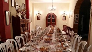 A long dining table set for a meal with white chairs, a chandelier, and a ceiling fan. - Beautiful house rociera to enjoy with your people (El Rocío)