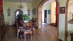 A dining area with a chandelier, a large potted plant, and a wooden dining table with chairs. - Beautiful house rociera to enjoy with your people (El Rocío)