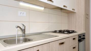 Una cocina moderna con un lavamanos de acero inoxidable, una estufa a gas y armarios de madera.