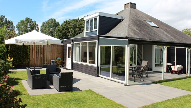 A modern house with a patio, outdoor furniture, and a covered area.