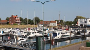 A marina with various boats docked, a pedestrian bridge, and buildings in the background.