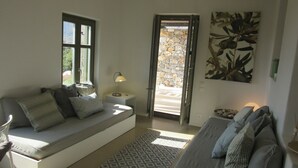 A modern living room with a sofa, a patterned rug, and a stone wall visible through an open door.