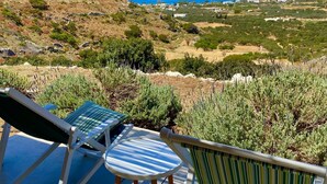 A deck with two lounge chairs and a small table overlooking a coastal landscape with a distant island.