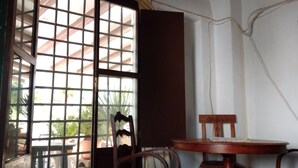 Una habitación con una mesa y sillas de madera, una ventana con vistas al exterior y una cortina.