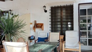 Un comedor rústico con muebles de madera, piso de baldosas y una ventana con rejas.