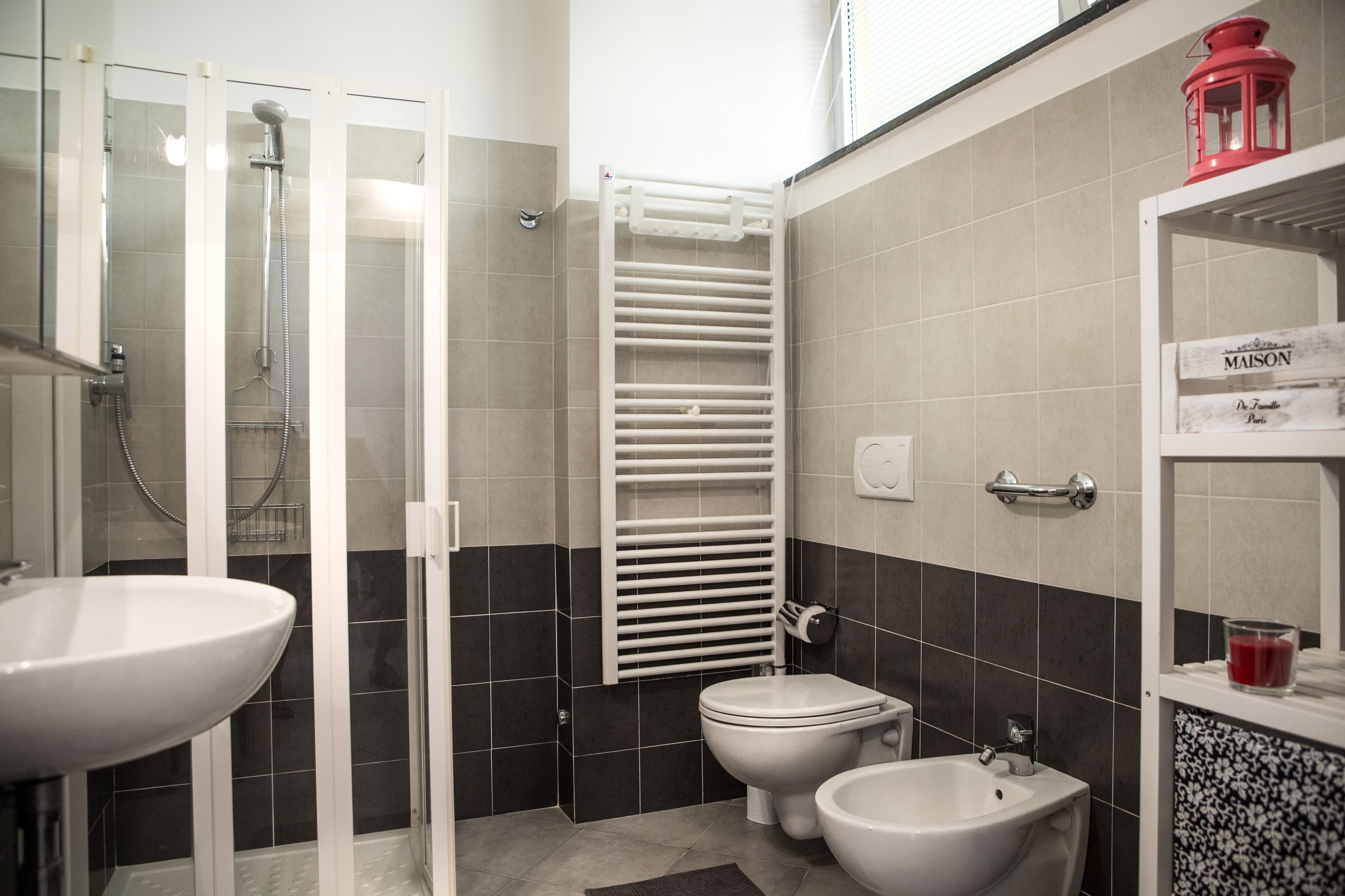 A bathroom with a glass-enclosed shower, a white sink, a toilet, and a bidet.