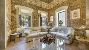 A room with stone walls, two patterned sofas, a glass coffee table, and a lamp. - Villas Marim Flamingo Villa (Olhão)