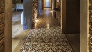 A hallway with patterned floor tiles, stone walls, and a wooden ceiling. - Villas Marim Flamingo Villa (Olhão)