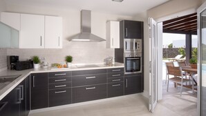 Una cocina moderna con armarios oscuros, una campana extractora de acero inoxidable y un horno.