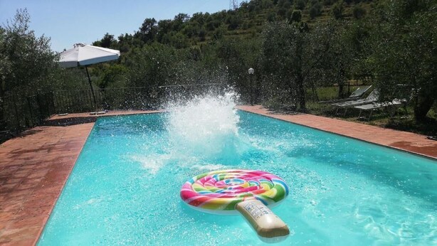 A swimming pool with a colorful inflatable ring and a water fountain. - Farmhouse in Chianti (gaiole in chianti)
