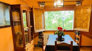 Zona pranzo con tavolo, sedie, un mobile e una finestra vista verde.