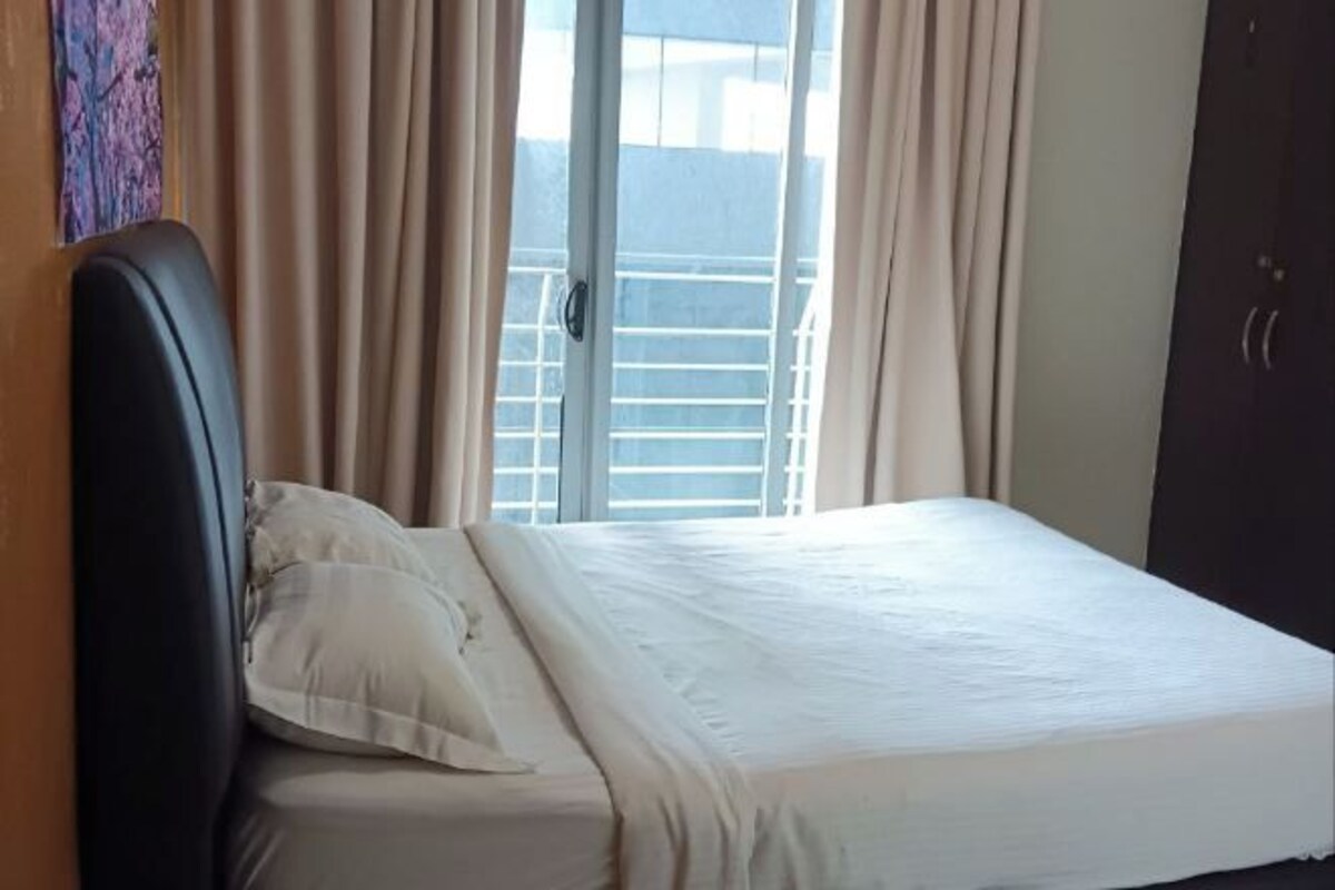 A hotel room with a bed, curtains, and a view of the outside.
