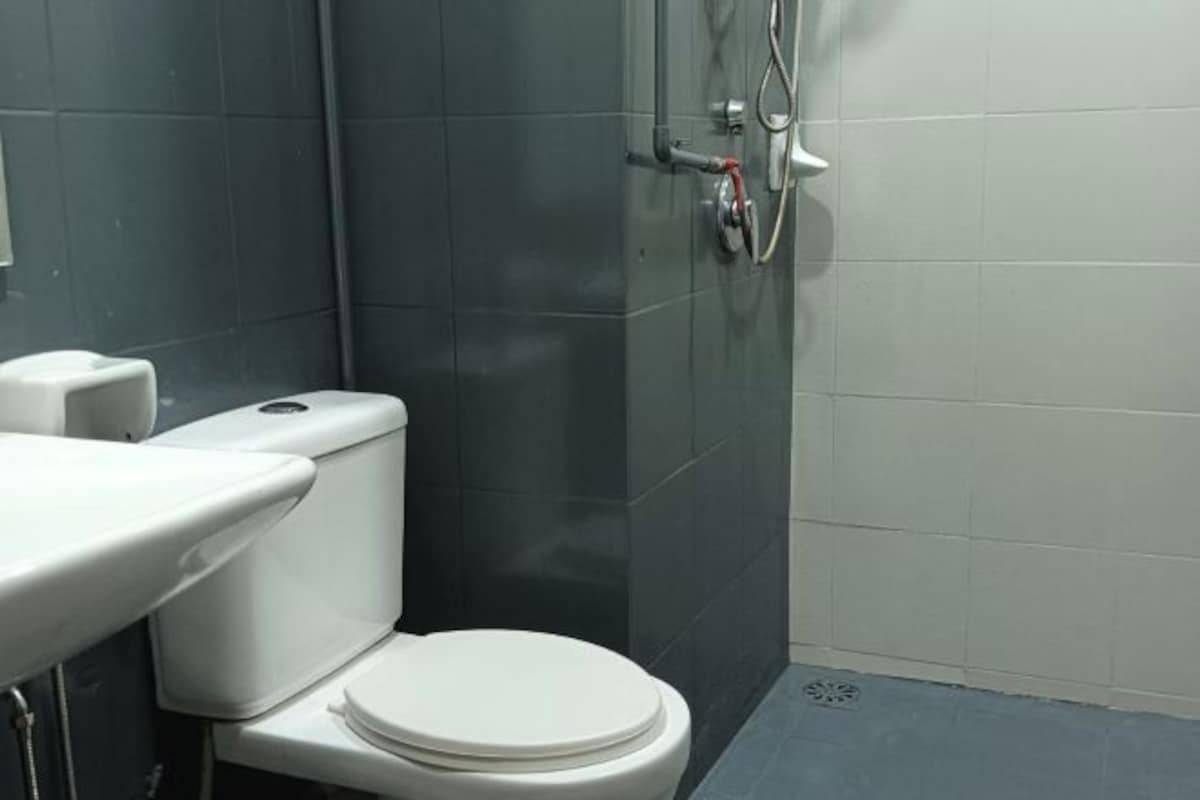 Une salle de bain avec des toilettes blanches, un lavabo et un espace douche.