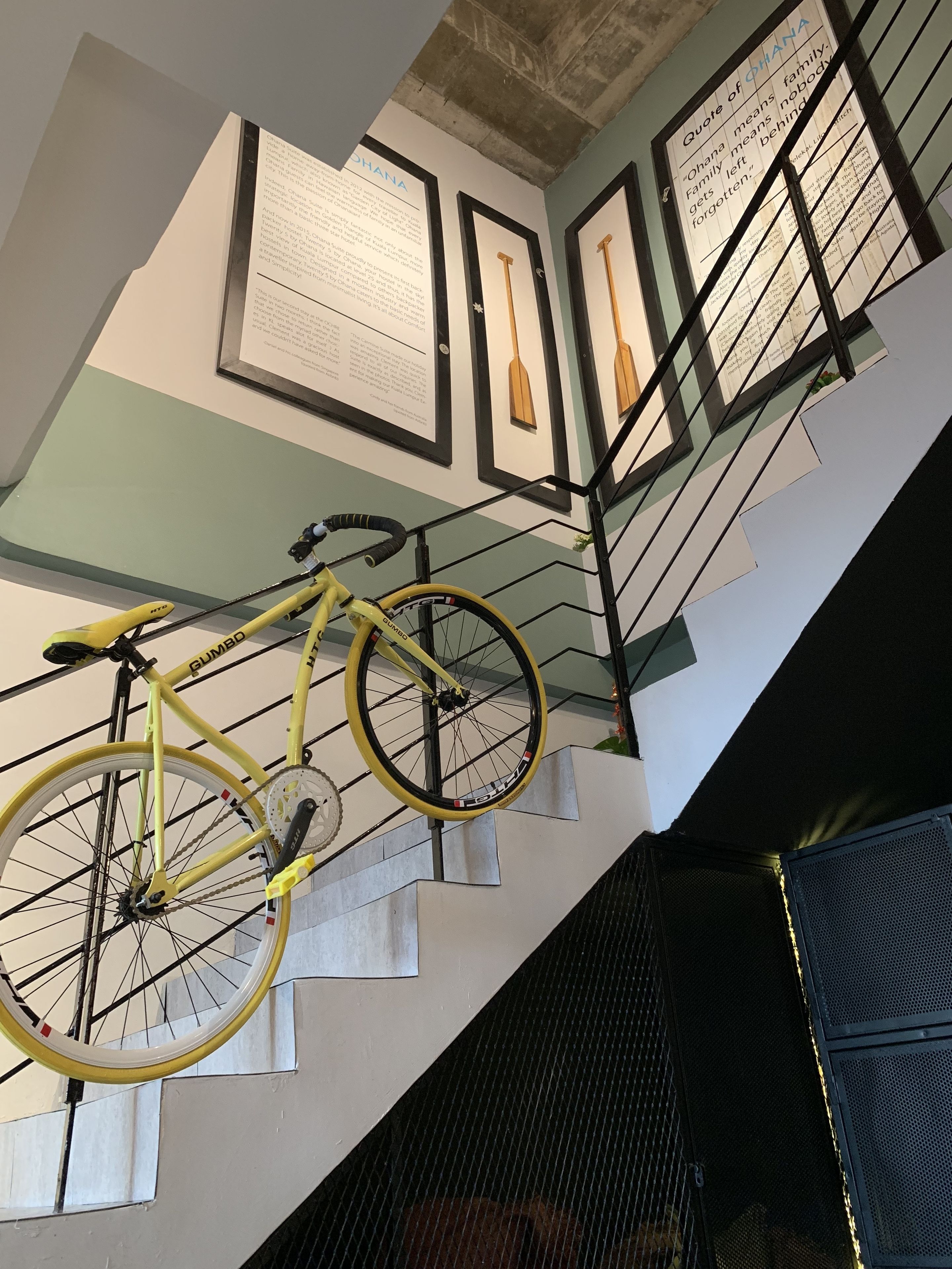 A staircase with a yellow bicycle hanging from the handrail.