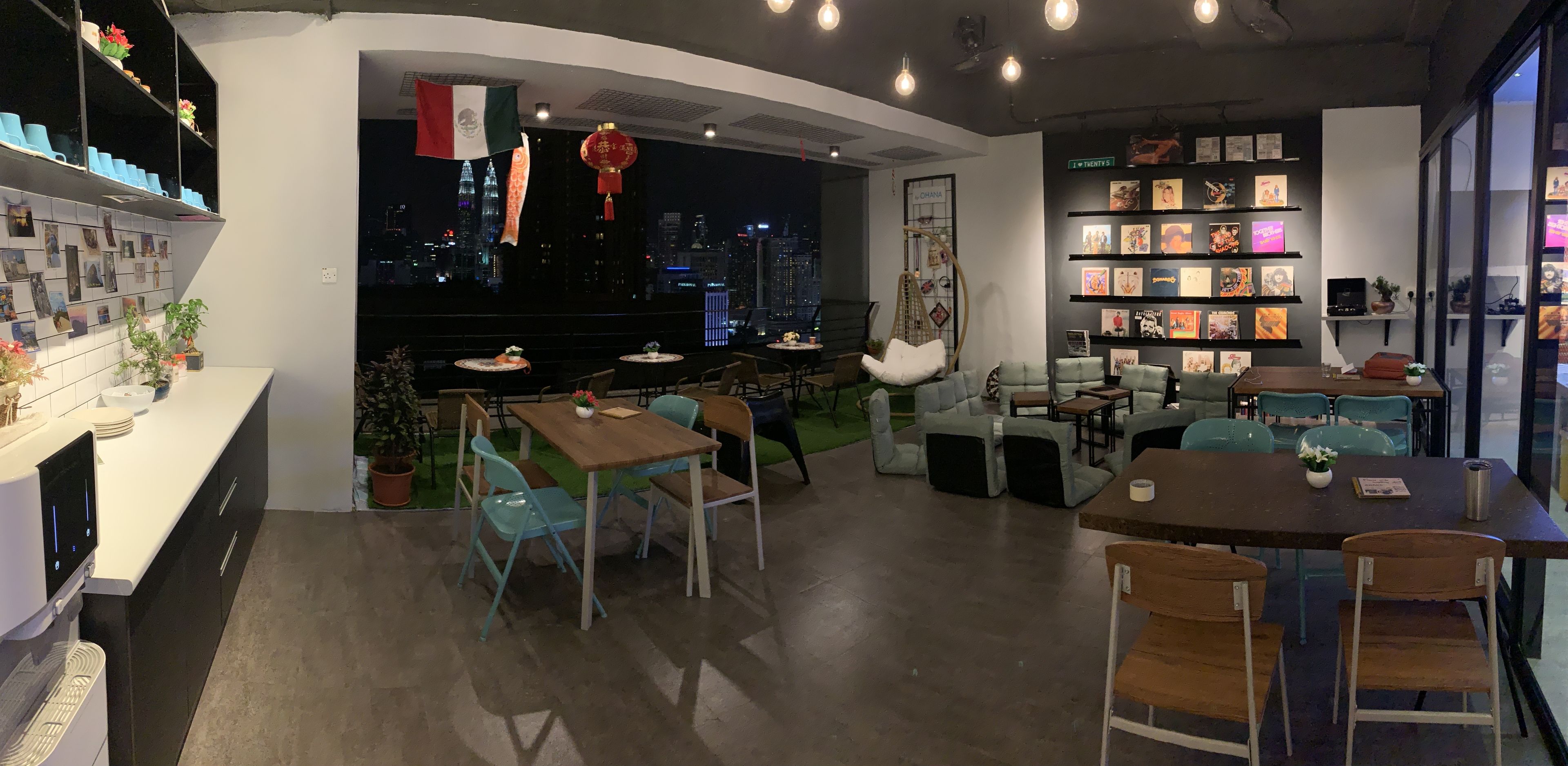 A modern restaurant with a city view, featuring a bar area, seating arrangements, and a wall of framed artwork.