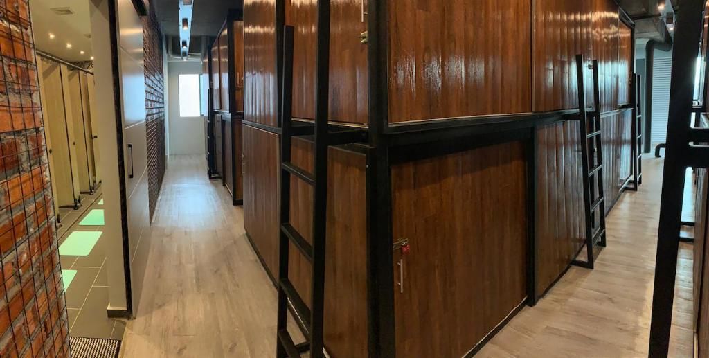 A hallway with wooden paneling and a tiled floor, leading to a bright room at the end.