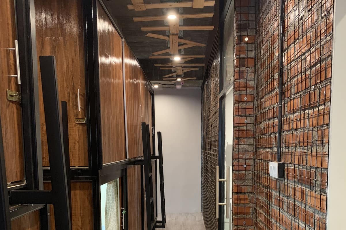 Un couloir étroit, avec un lambris en bois d’un côté et un mur de briques de l’autre.