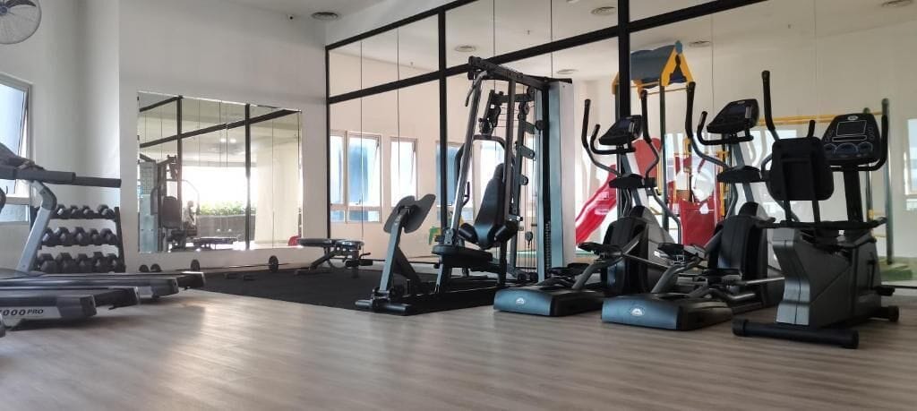 A gym with cardio machines, weightlifting equipment, and dumbbells.