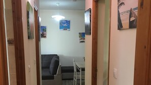 A narrow hallway with wooden doors, a grey sofa, a small table, and wall-mounted pictures. - Beautiful T3 in tropical forest with swimming pool (saint joseph)