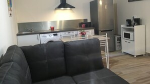A modern kitchen with stainless steel appliances, a black range hood, and a white refrigerator. - Beautiful T3 in tropical forest with swimming pool (saint joseph)