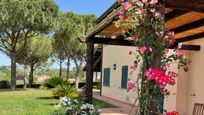 A rustic building with a garden, featuring white and pink flowers, wooden furniture, and a clear sky. - Tenuta Santa Cristina - Luxury 8 beds Villa w/ private Pool and Tennis near Rome (Lazio)