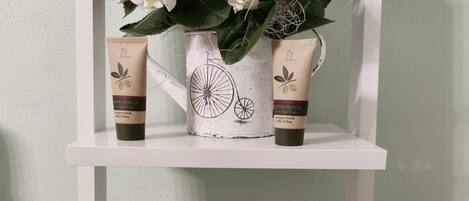 A shelf with a white vase containing white flowers, two skincare products, and a woven basket.