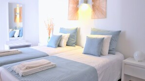 Habitació d'hotel amb dos llits, una tauleta de nit, un mirall i aplics de paret.