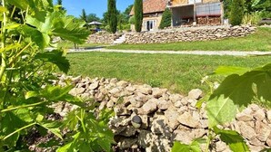 Una casa con un muro de piedra y un patio cubierto de césped.