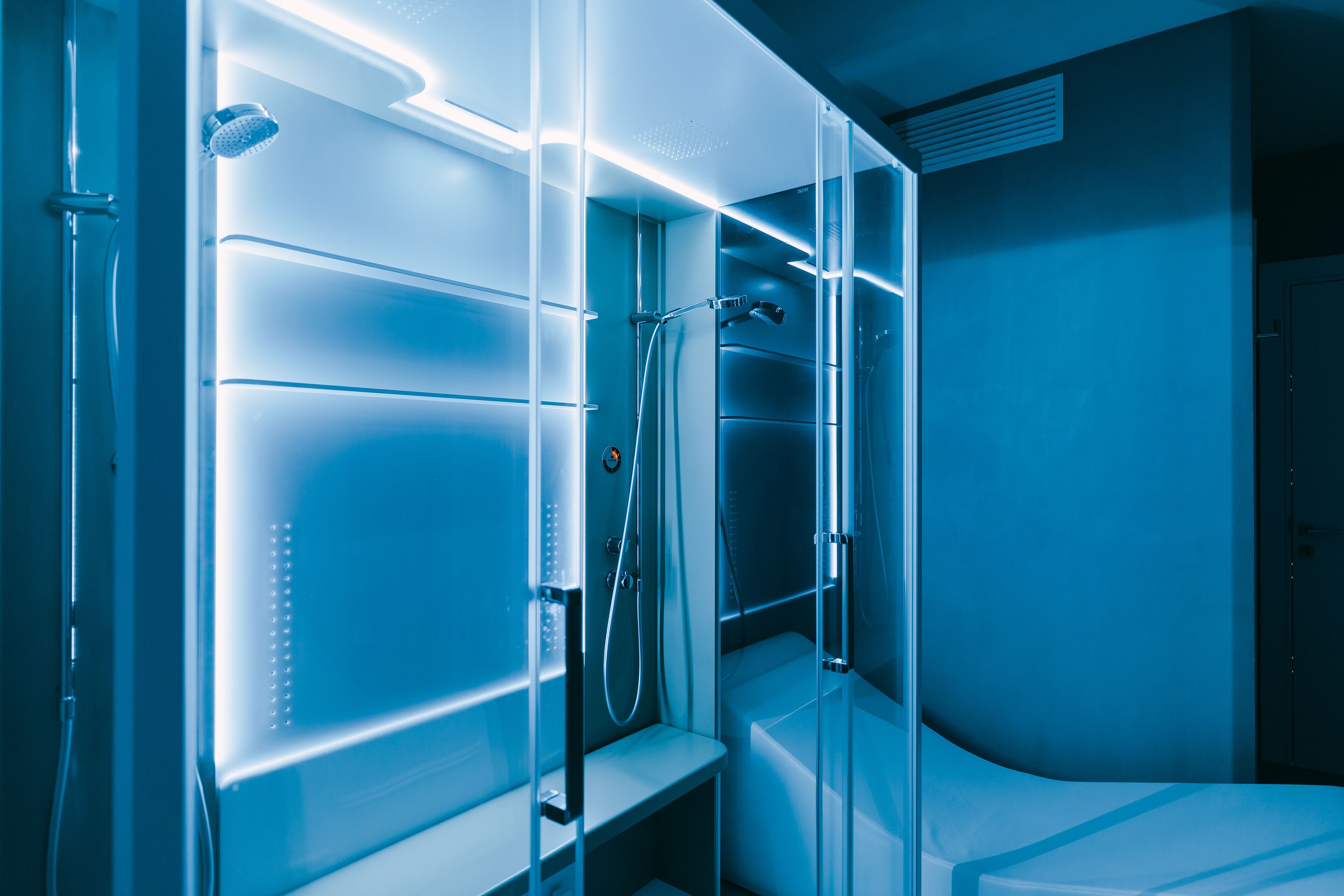 Une salle de bain moderne avec une douche à parois de verre, des étagères intégrées et un lavabo blanc.