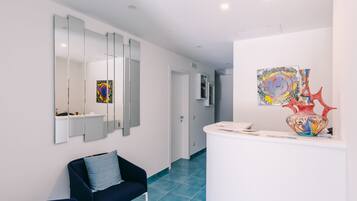 A modern hotel lobby with a reception desk, a blue sofa, and artwork on the walls.