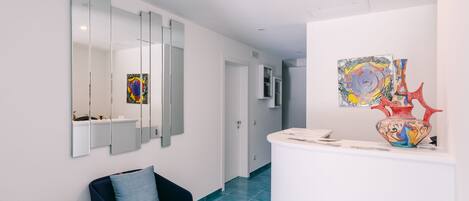 A modern hotel lobby with a reception desk, a blue sofa, and artwork on the walls.