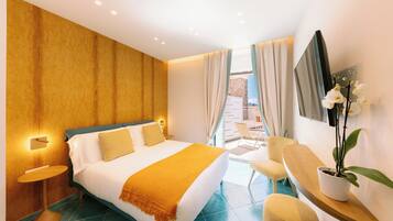 Ein modernes Hotelzimmer mit einem großen Bett, einem kleinen Tisch, einem Sessel und einer Topfpflanze.