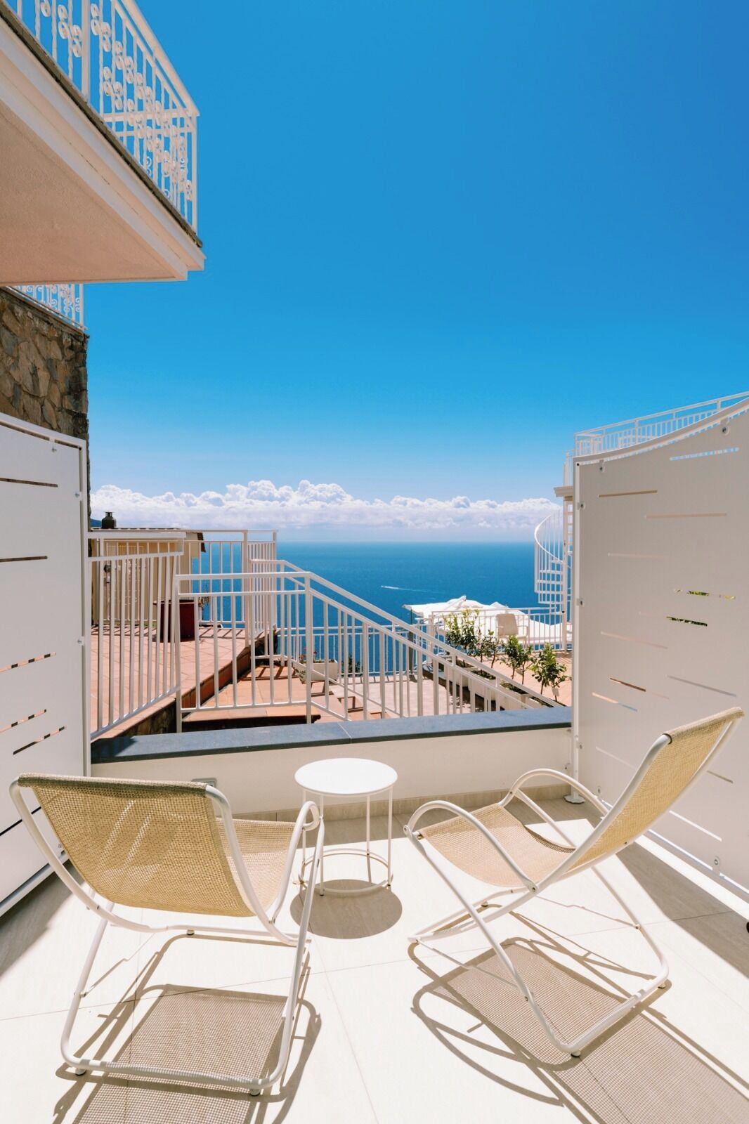 A balcony with white metal railings, wicker chairs, and a small round table.