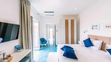 A modern hotel room with a large bed, a flat-screen TV, a desk with a computer, and a chair.